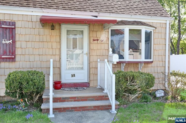 entrance to property featuring a shingled roof