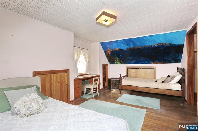 bedroom with ornamental molding and wood finished floors