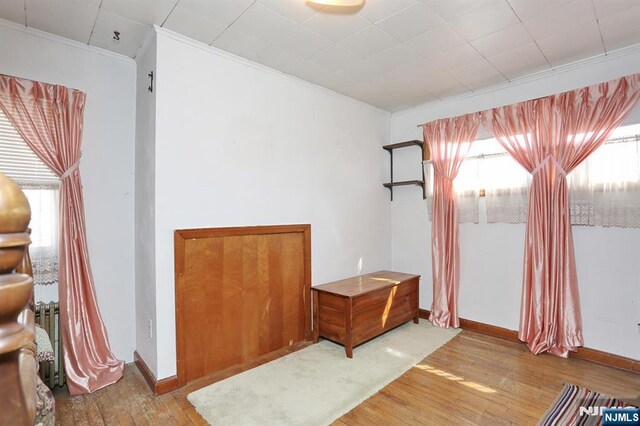 spare room with baseboards, wood finished floors, and ornamental molding