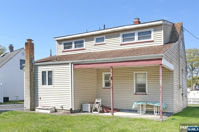 back of property featuring a shingled roof and a lawn