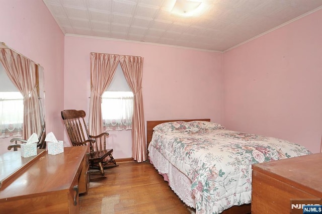 bedroom featuring ornamental molding, wood finished floors, and baseboards