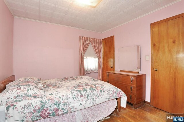 bedroom featuring wood finished floors and ornamental molding