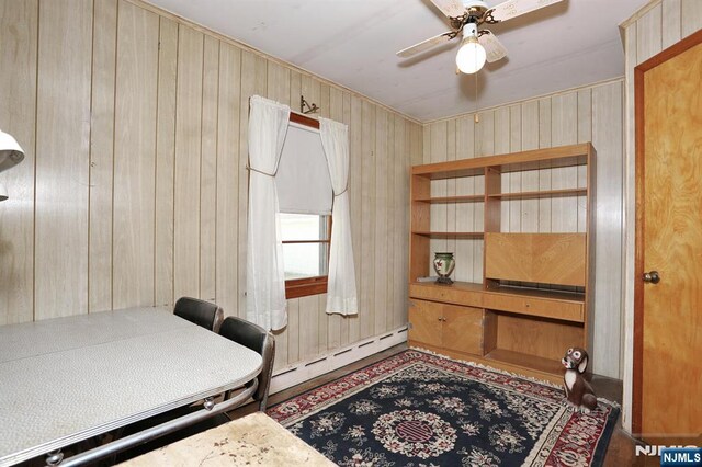 office area featuring wood walls, ceiling fan, and baseboard heating