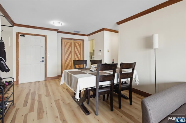 dining room with crown molding, visible vents, light wood-style flooring, and baseboards