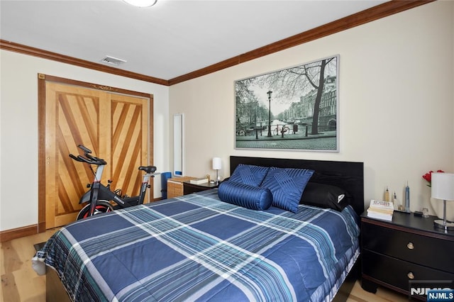 bedroom featuring baseboards, visible vents, wood finished floors, and ornamental molding