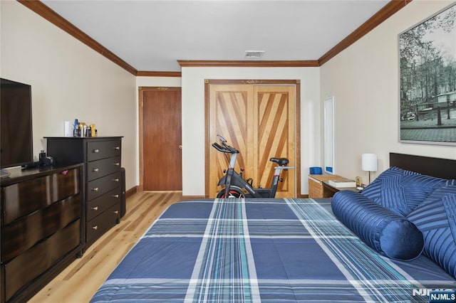 bedroom featuring visible vents, light wood-type flooring, crown molding, and baseboards