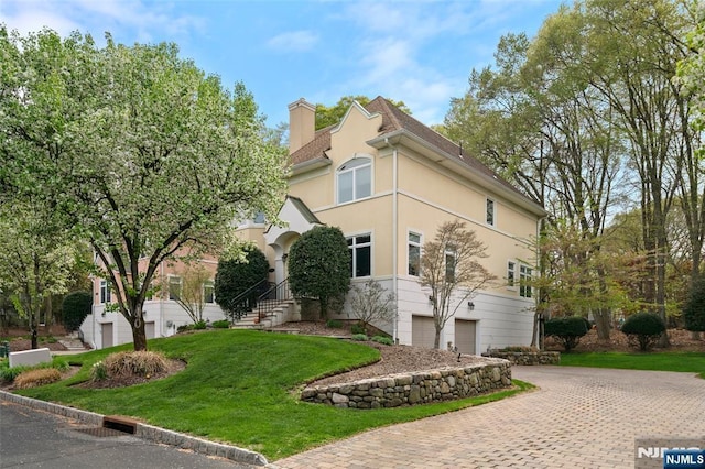 161 Winding Way, Old Tappan, NJ 07675 - view of front facade with a garage, a chimney, a front yard, stucco siding, and decorative driveway
