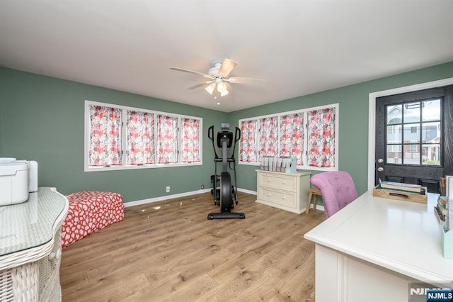 office space with baseboards, a ceiling fan, and light wood-style floors