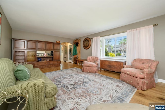 living room featuring arched walkways, wood finished floors, and baseboards
