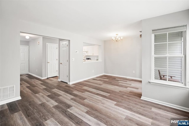 2304 Wendover Dr, Pequannock Township, NJ 07444 - unfurnished living room with wood finished floors, visible vents, a notable chandelier, and baseboards