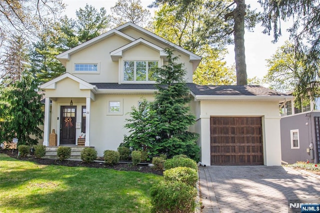 view of front of property with an attached garage, a front yard, decorative driveway, and stucco siding