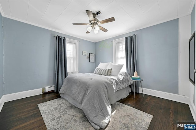 bedroom with a baseboard radiator, wood finished floors, ornamental molding, and multiple windows