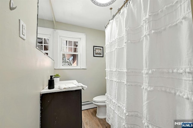 bathroom featuring wood finished floors, toilet, vanity, and a baseboard radiator