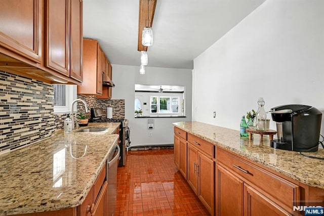 kitchen featuring brown cabinets, decorative backsplash, a sink, stainless steel appliances, and brick patterned floor