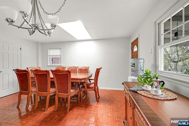 dining area featuring a skylight, an inviting chandelier, brick patterned floor, and plenty of natural light