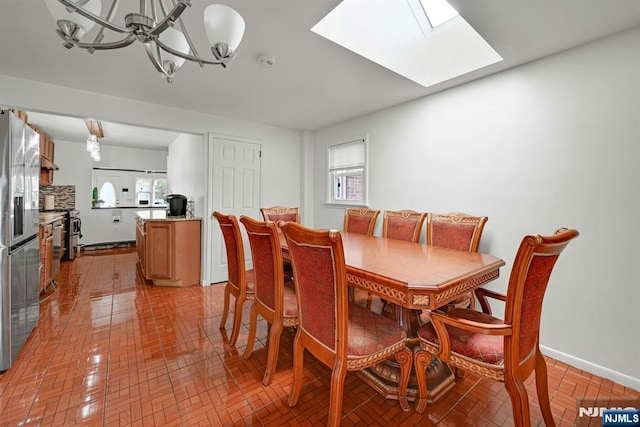 dining space with a fireplace, a skylight, an inviting chandelier, and baseboards