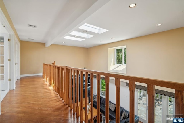hall featuring recessed lighting, an upstairs landing, visible vents, a skylight, and wood finished floors
