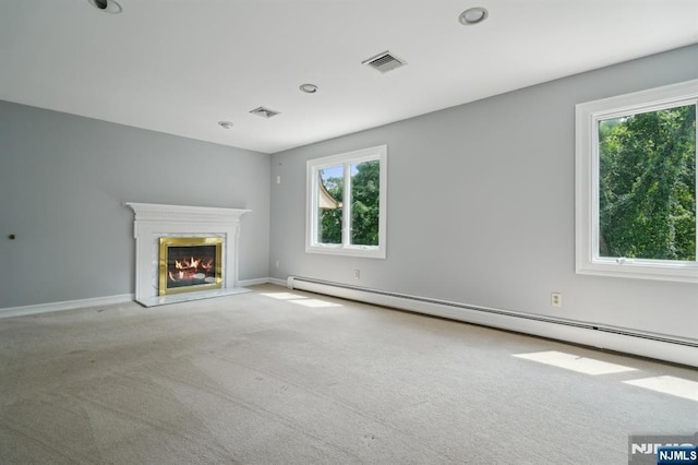 unfurnished living room with a wealth of natural light, visible vents, a baseboard heating unit, and carpet