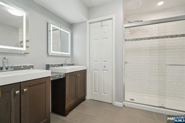 bathroom featuring a stall shower, two vanities, a sink, and tile patterned floors