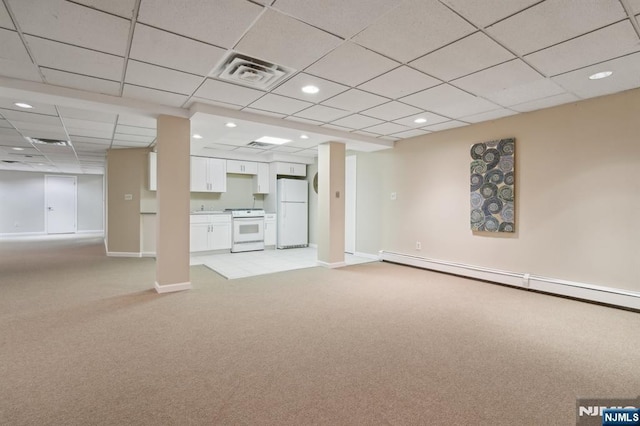 below grade area featuring a drop ceiling, freestanding refrigerator, light carpet, baseboards, and visible vents