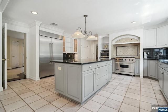 kitchen with light tile patterned floors, open shelves, a center island, visible vents, and premium appliances
