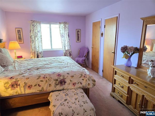 bedroom featuring light colored carpet and two closets