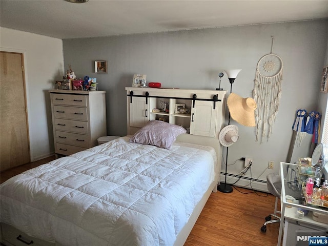 bedroom with wood finished floors and baseboard heating