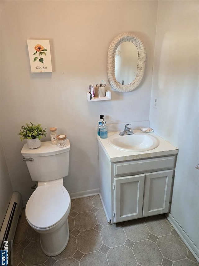 half bath with a baseboard heating unit, toilet, tile patterned flooring, and vanity