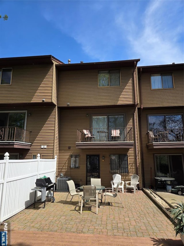 rear view of property with central air condition unit, fence, and a patio area