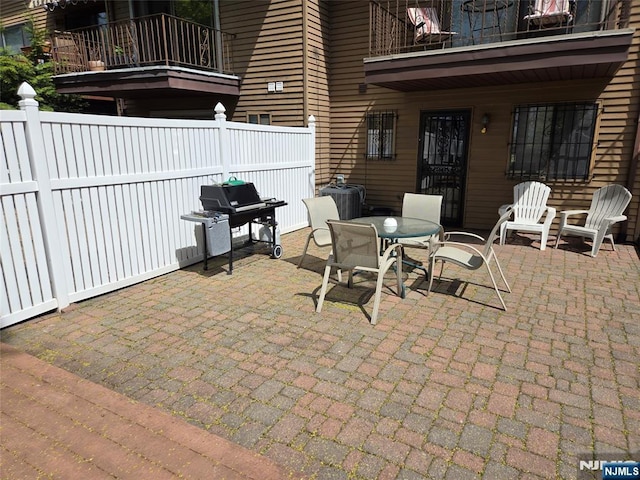 view of patio / terrace with fence, outdoor dining space, and a balcony