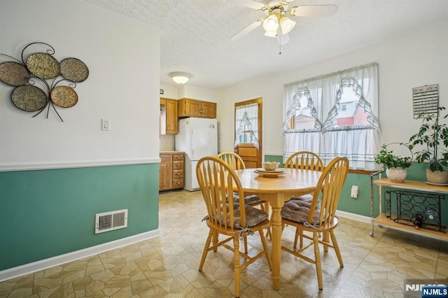 dining space featuring a textured ceiling, visible vents, a ceiling fan, and baseboards