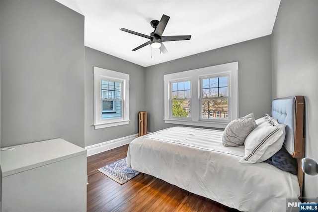 bedroom with wood finished floors, ceiling fan, baseboards, and multiple windows