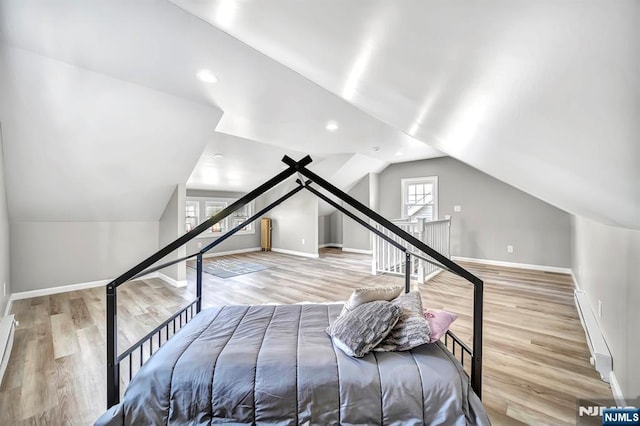 bedroom with baseboards, baseboard heating, wood finished floors, and lofted ceiling