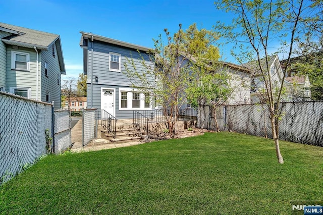 rear view of property with a fenced backyard and a lawn