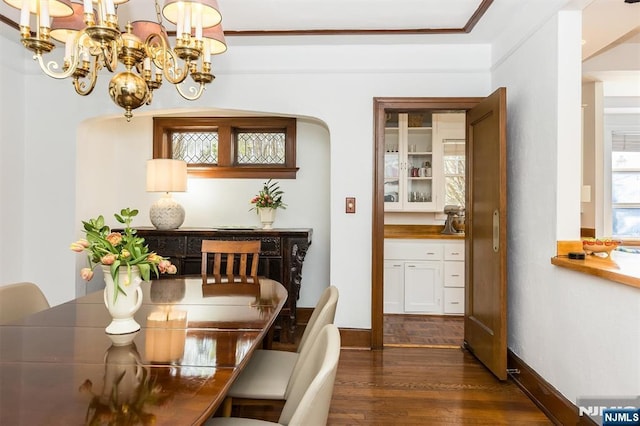 dining area with arched walkways, a notable chandelier, baseboards, and dark wood finished floors