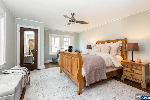 bedroom with baseboards, ornamental molding, ceiling fan, and light wood-style flooring