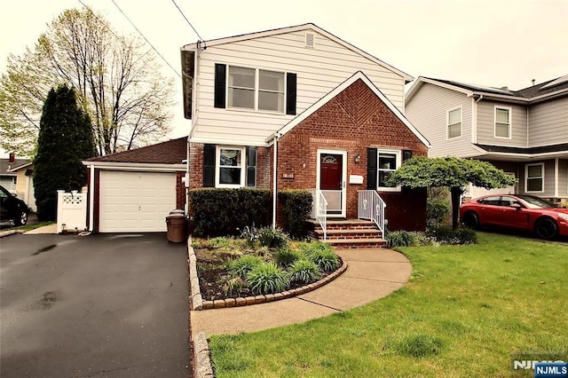 view of front of house with a front yard, a garage, aphalt driveway, and brick siding