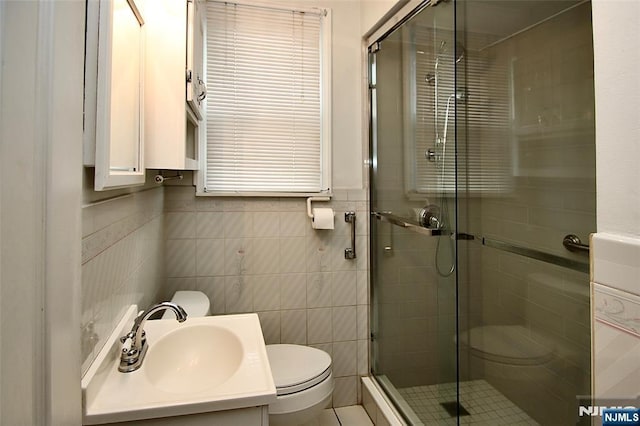 full bathroom with toilet, a stall shower, tile walls, and vanity