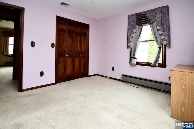 unfurnished bedroom featuring a baseboard heating unit, a closet, visible vents, light carpet, and baseboards