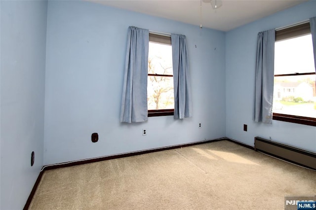 empty room with baseboard heating, baseboards, ceiling fan, and carpet