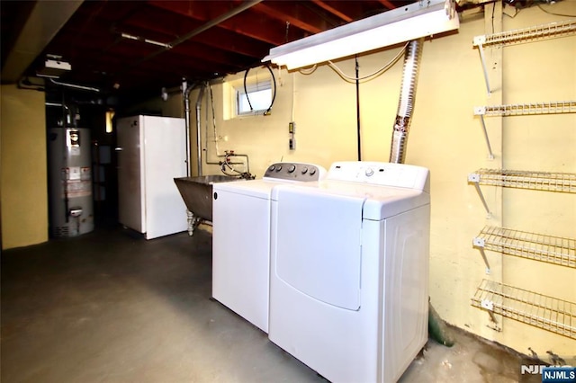 laundry area with water heater, washer and clothes dryer, laundry area, and a sink