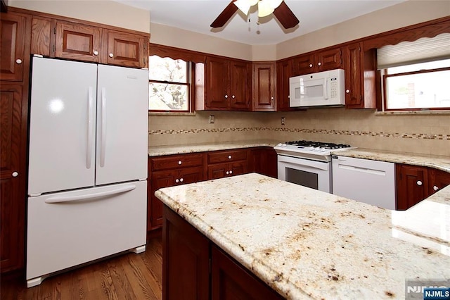 kitchen with light stone countertops, ceiling fan, dark wood-style flooring, and white appliances