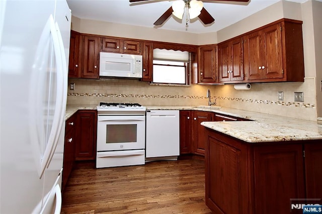 kitchen featuring decorative backsplash, a sink, ceiling fan, white appliances, and a peninsula