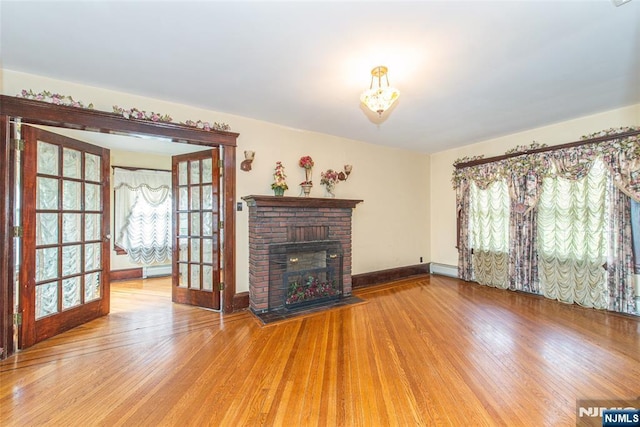 117 Saint Marys Pl, Nutley, NJ 07110 - unfurnished living room with french doors, a fireplace, baseboards, a baseboard heating unit, and light wood-style flooring