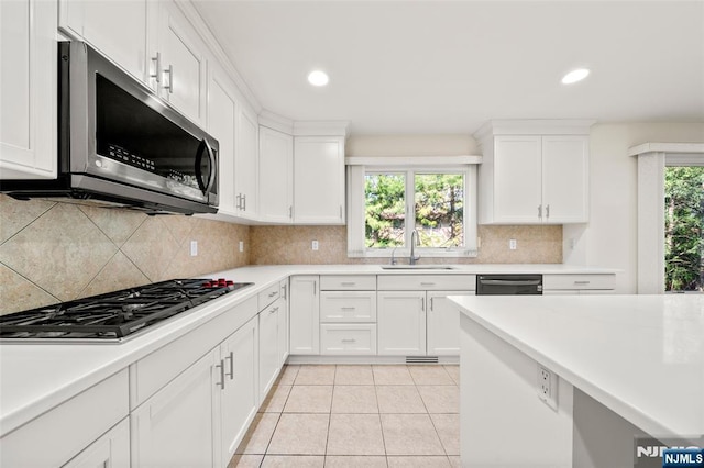 kitchen with a sink, appliances with stainless steel finishes, white cabinets, and light countertops