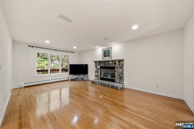 unfurnished living room with visible vents, wood finished floors, a stone fireplace, baseboard heating, and recessed lighting