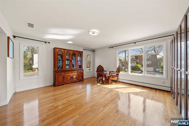 living area with a healthy amount of sunlight, baseboards, light wood finished floors, and visible vents