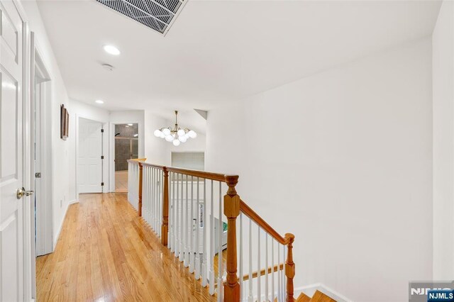 hall featuring visible vents, baseboards, recessed lighting, light wood-type flooring, and an upstairs landing