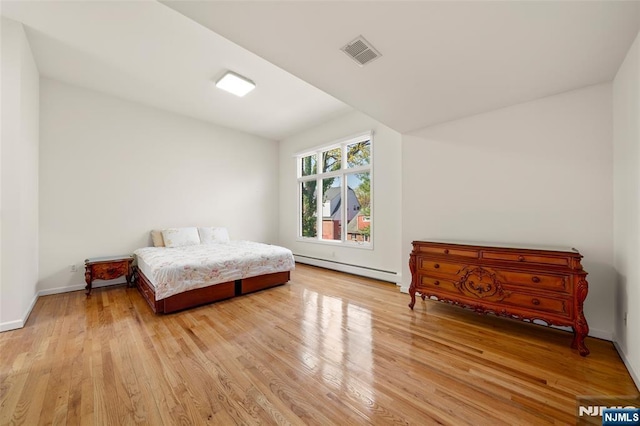 bedroom featuring visible vents, light wood finished floors, baseboards, and baseboard heating