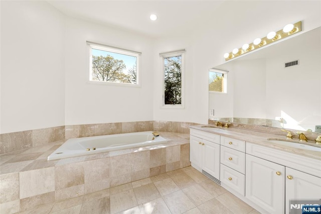 bathroom with a sink, double vanity, a bath, and visible vents